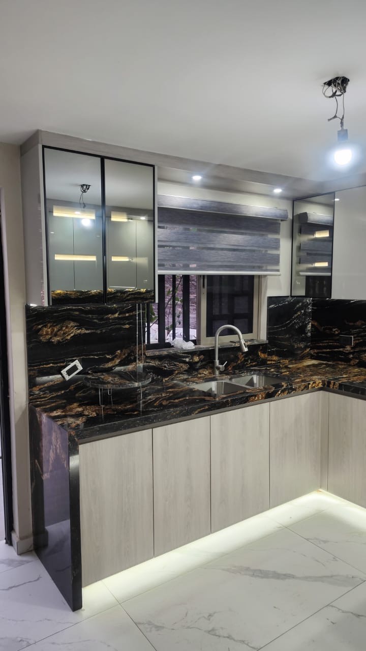 Cocina con cubierta y backsplash de granito negro con veta dorada y vitrinas superiores