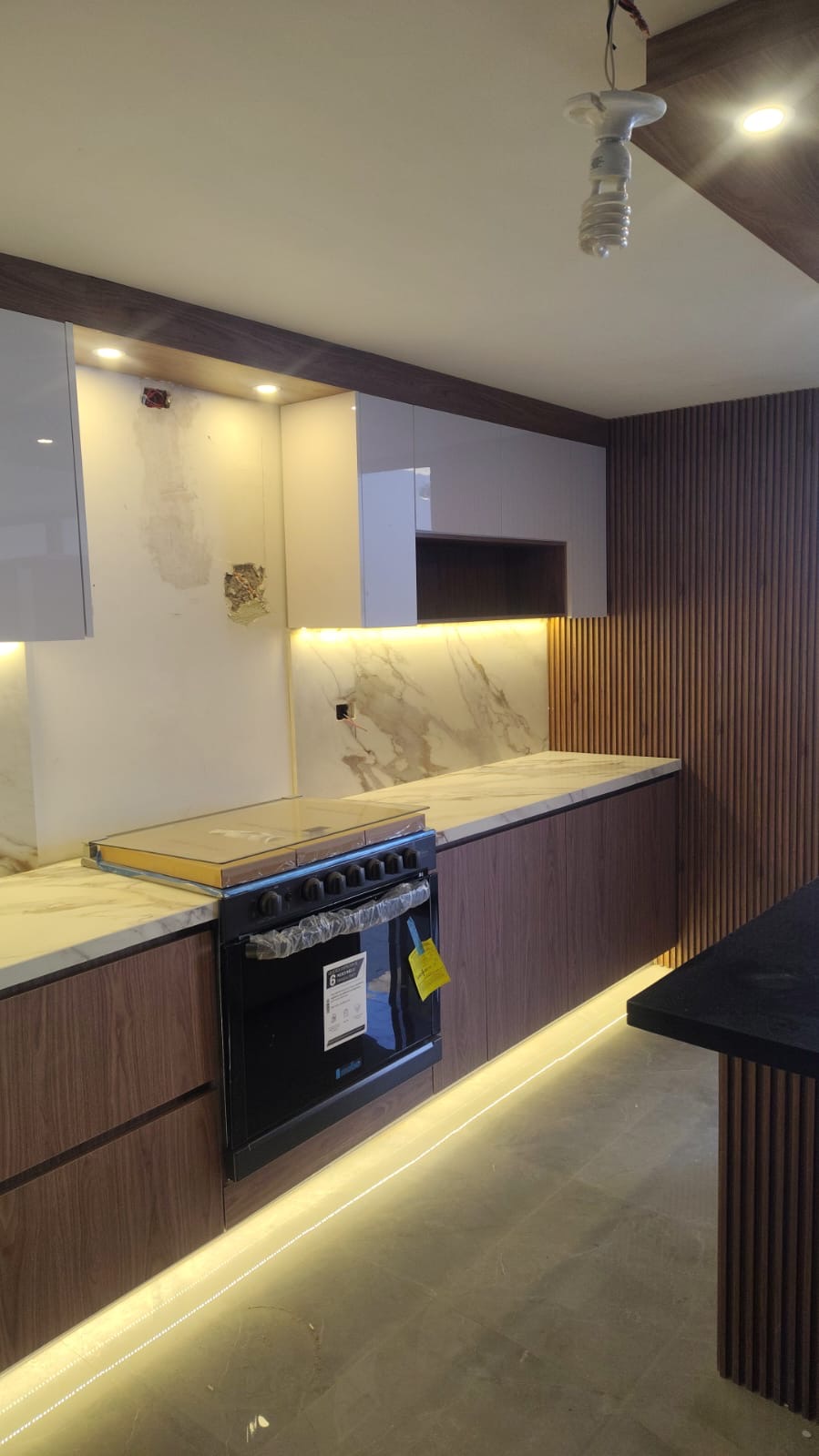 Cocina con muro de celosía de madera, cubierta de mármol y gabinetes color nogal