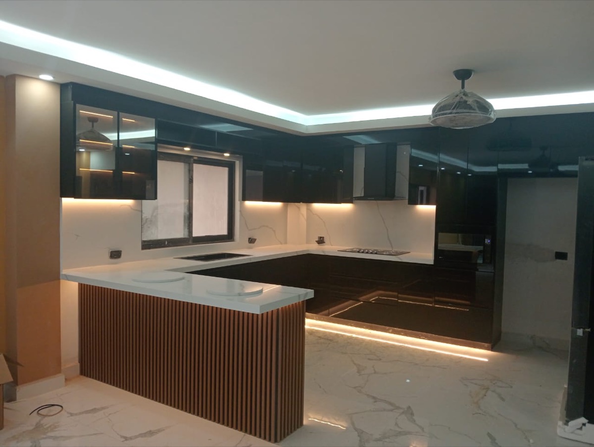 Cocina negra de alto brillo con barra de celosía de madera y piso de mármol